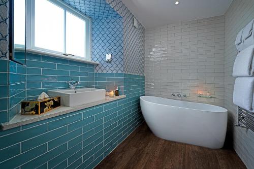 巴利瓦根Monks Ballyvaughan的蓝色瓷砖浴室设有浴缸和水槽