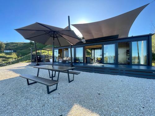 HangatikiWaitomo Retreat的一个带野餐桌和雨伞的房子