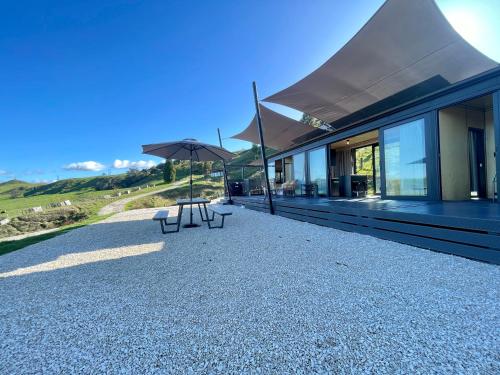 HangatikiWaitomo Retreat的一座带两个长椅和遮阳伞的建筑