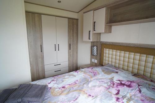 亨斯坦顿Heacham Sunset lodge Platinum van的一间卧室配有一张床和白色橱柜