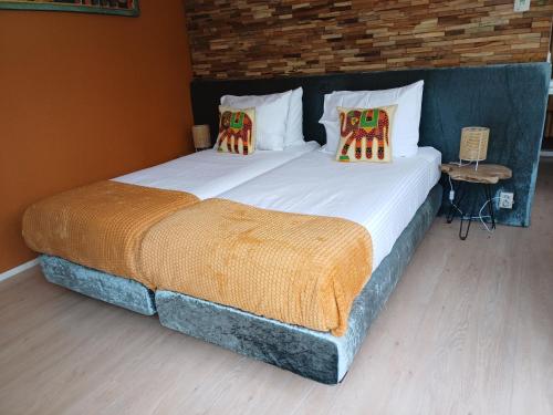 费嫩达尔East Meets West Bed and Breakfast的一间卧室设有两张单人床、枕头和砖墙