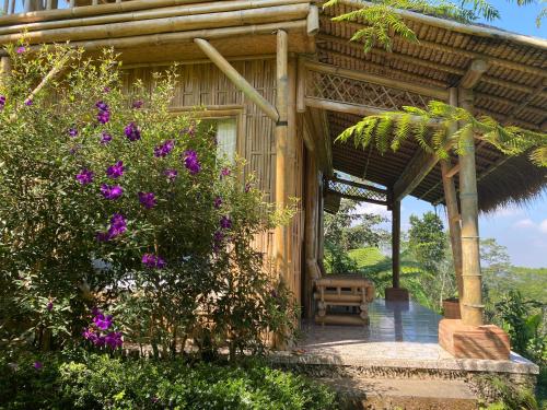 BaturitiLembah Cinta Mayungan的一座带紫色花朵的木房子的门廊