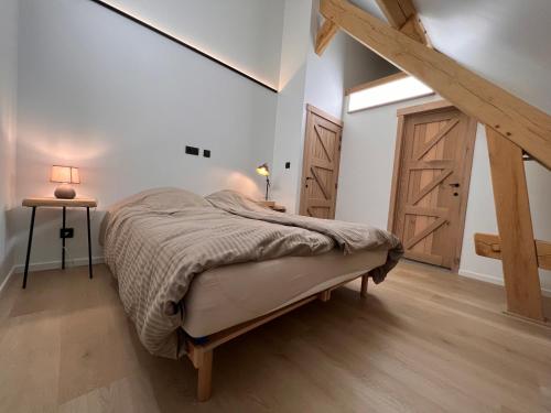 Hechtel-EkselDe Kamert的一间卧室设有一张大床,铺有木地板