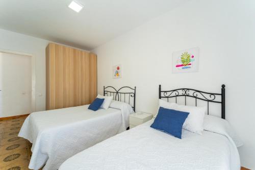 巴尔巴特Apartamento Estudio Acuario Frente Mar的配有白色床单和蓝色枕头的客房内的两张床