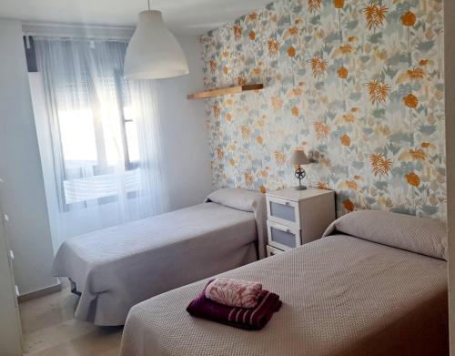 休达Beatiful and full-equipped flat in the city center的一间卧室设有两张床和鲜花墙