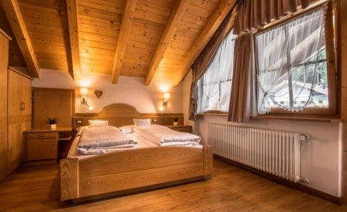 拉维拉Ciasa Montanara的一间卧室设有一张床和一个大窗户
