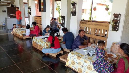 黎明之村Wow Farm House & Resort near Pondicherry的一群坐在房间里桌子的人