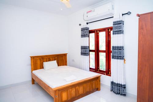 贾夫纳Thisha Hotel的一间卧室设有一张床和一个窗口