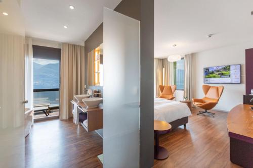 布里萨戈Parkhotel Brenscino Brissago的配有一张床和一张书桌的酒店客房