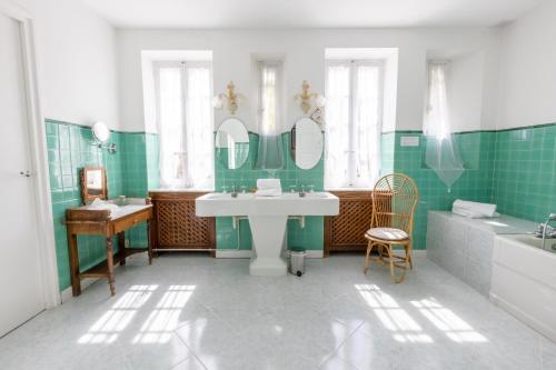 弗卢尔Château de Floure - Hôtel, restaurant, SPA et piscine extérieure chauffée的浴室设有绿色瓷砖、水槽和浴缸