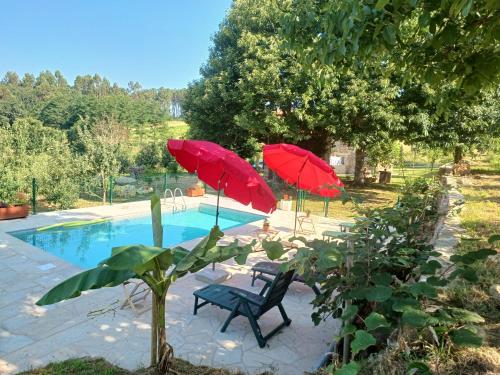 A Quinta Das Maceiras的游泳池畔的两把红伞和两把椅子