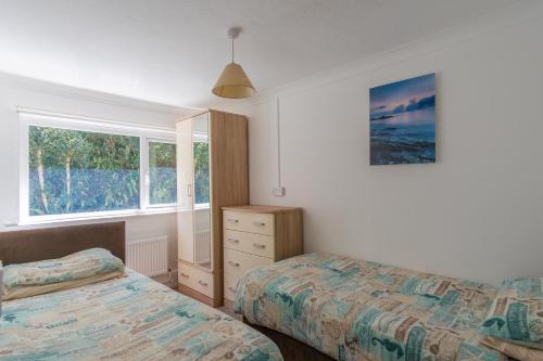 比迪福德Deluxe Kipling Villa with Sea Views的一间卧室设有两张床、一个梳妆台和两个窗户。