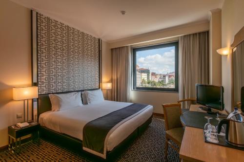 里斯本世界酒店的配有一张床、一张书桌和一扇窗户的酒店客房