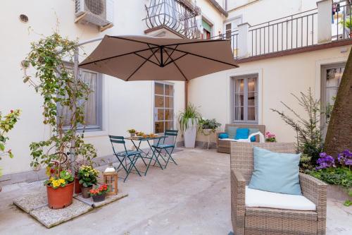 卢卡Il Cortile di Elisa & our flats的庭院配有遮阳伞、椅子和桌子。