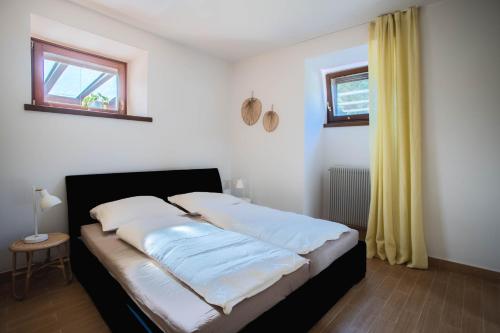 托尔博莱Villetta al lago的一间卧室配有一张带白色床单的床和一扇窗户。