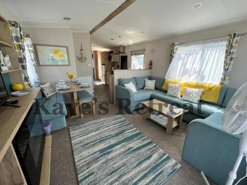 纽基Kayes Retreat Three bed caravan Newquay Bay Resort Quieter area of park的客厅配有蓝色的沙发和桌子