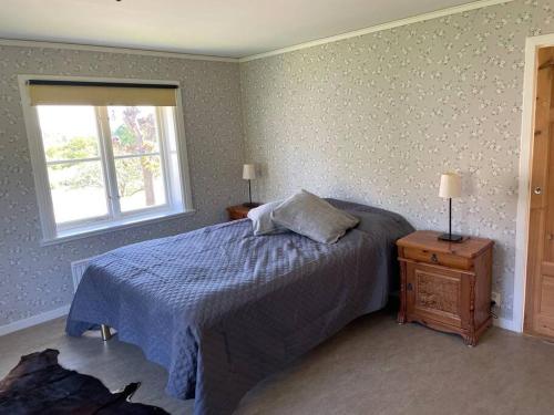 斯特兰奈斯Flygeln的一间卧室配有一张带蓝色棉被的床和窗户。
