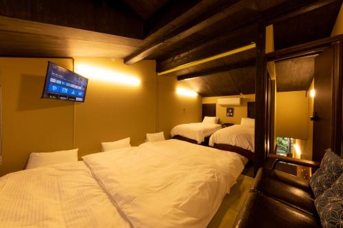 高山Tsuki-Akari Takayama - Japanese modern Vacation Stay with an open-air bath的一间卧室设有两张床,墙上配有电视。