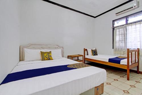 日惹SPOT ON 92623 Mw 46 Guesthouse的一间卧室设有两张床和窗户。