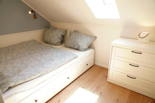 霍尔斯泰因地区诺伊斯塔特FeWo Suite Spaltsberg am Binnenwasser的卧室配有白色的床和梳妆台。