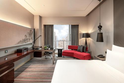 重庆重庆富力艾美酒店的酒店客房,配有一张床和一张红色椅子