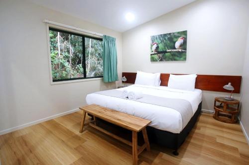 Lake Eacham钱伯斯野生动物雨林旅舍的一间卧室设有一张大床和一个窗户。