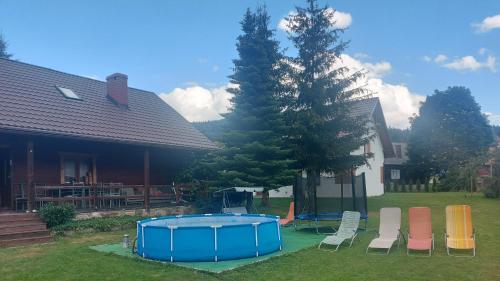 SablówkaPokoje Gościnne u Huberta的一组椅子和一个院子内的游泳池