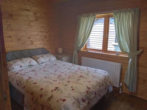 斯沃弗姆Bishy Barnabees country lodge with hot tub的一间卧室设有一张床和一个窗口