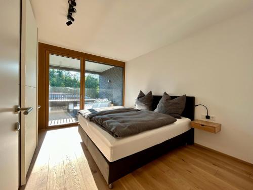 布雷根茨Seeparkvilla – Wohlfühlen am See und im Grünen的一间卧室设有一张大床和一个滑动玻璃门