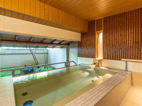 伊豆Shuzenji Onsen Katsuragawa的木墙客房的按摩浴缸