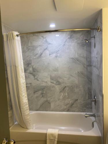 金斯顿Ramada by Wyndham Kingston的带浴缸和大理石淋浴帘的浴室