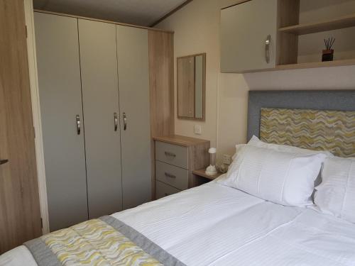 米尔福德昂西2 Bedroom Lodge, Milford on Sea的一间卧室配有一张带白色床单和橱柜的床。