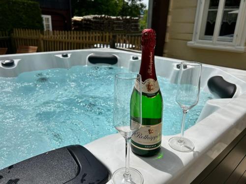 大舍瑙Ferienwohnung Ornella mit Sauna, Whirlpool的热水浴池内的一瓶香槟和两杯葡萄酒