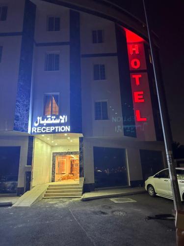 麦地那ريف الشرق للشقق الفندقية的停车场内有红色 ⁇ 虹灯标志的酒店