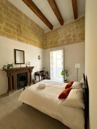 瓦莱塔L'Artist Casa Micallef的一间卧室设有一张大床和一个壁炉