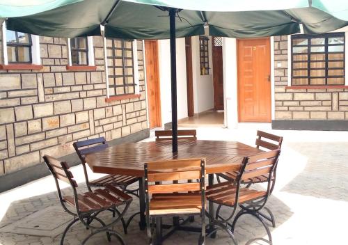 AwasiAster Suites Kisumu的一把伞下的木桌和椅子