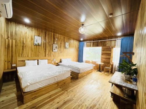 宁平Tuyet's hostel的配有木墙和木地板的客房中的两张床