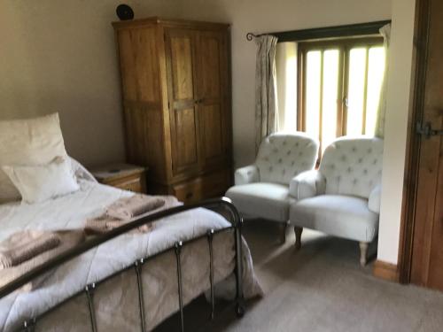 博德明Owletts Barn B&B的一间卧室配有一张床、两把椅子和一个窗户