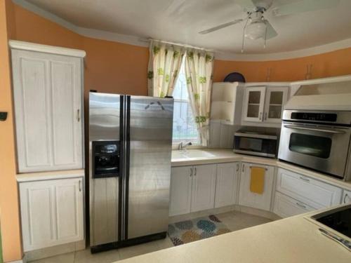 圣菲利普Cottage: 7 minutes from airport!的厨房配有白色橱柜和不锈钢冰箱