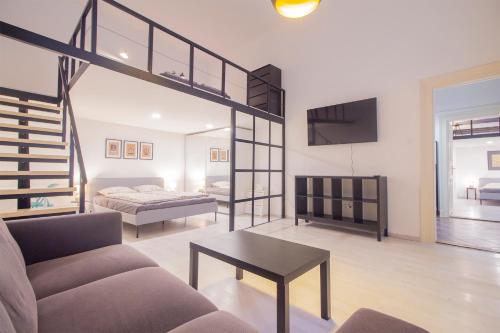 布达佩斯Industrial Double Loft Apartment的带沙发和床的客厅以及楼梯。