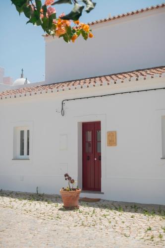 维拉诺瓦德卡塞拉A Casa de Cima - Cacela Velha的一座白色的建筑,有红门和盆栽植物