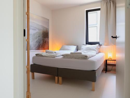 海边的艾格蒙特Zilt aan Zee的一间卧室配有一张带白色床单的床和一扇窗户。