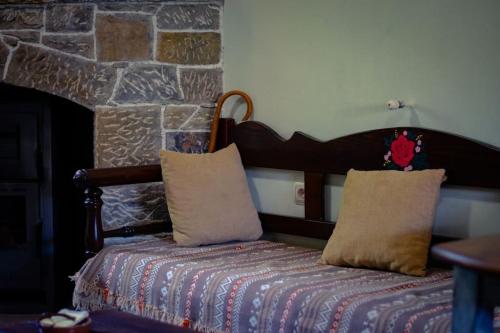 KamariótisΜουριές的一张带两个枕头的床和石墙