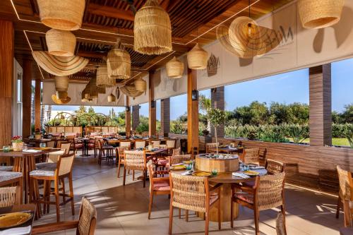 阿依纳帕NissiBlu Beach Resort的餐厅设有桌椅和大窗户。