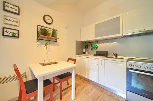 弗济内Studio Apartman Roxy的厨房配有白色橱柜和桌椅
