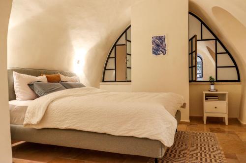 耶路撒冷Cozy Heritage Home Jerusalem的一间卧室设有一张大床和两个窗户。