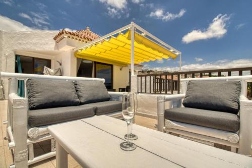 法纳贝海滩Luxury Penthouse Sea View Jacuzzy & pool wiffi free的天井配有两把椅子和一张带葡萄酒玻璃的桌子