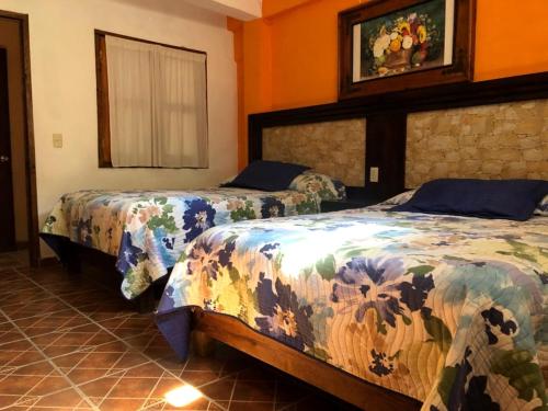 希利特拉Hotel Posada San Agustin的橙色墙壁客房的两张床