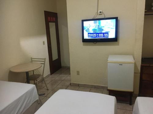 里贝朗普雷托HOTEL CENTER Ribeirão的一间墙上配有电视和一张桌子的房间
