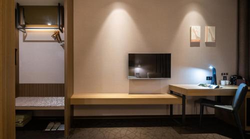 泰山丽京栈酒店的客房设有一张桌子,墙上配有电视